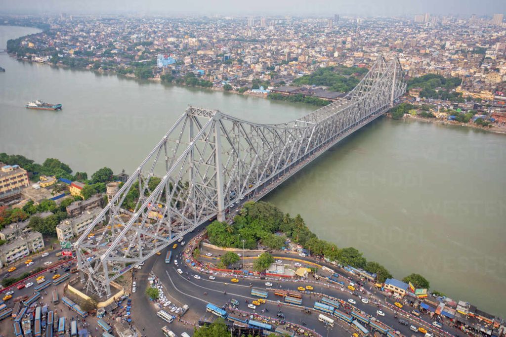 Aerial view of architectural landmark Howrah bridge or Rabindra Setu over the Hooghly River at day in Kolkata, West Bengal, India.